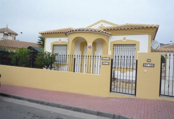 A residential building with a yellow facade, two arched doorways, and a gated entrance.