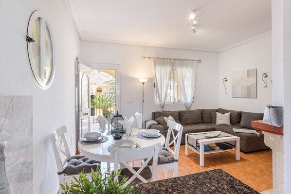 A living room with a sofa, dining table, chairs, and a coffee table.
