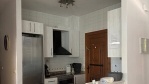 Une cuisine dotée de meubles blancs, d’un réfrigérateur en acier inoxydable, d’un four encastré et d’un plan de travail en granit.