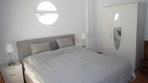 Une chambre à coucher avec un lit, des lampes de chevet, une armoire et un miroir rond accroché au mur.