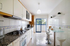 Una cucina moderna con mobili bianchi, un piano di lavoro in granito e un tavolo da pranzo in vetro.