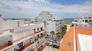 Un hôtel à plusieurs étages, doté de balcons, offrant une vue sur la plage et disposant d’un parking.