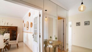 Une pièce comprenant un coin repas, un meuble en bois, une table en verre et un luminaire.