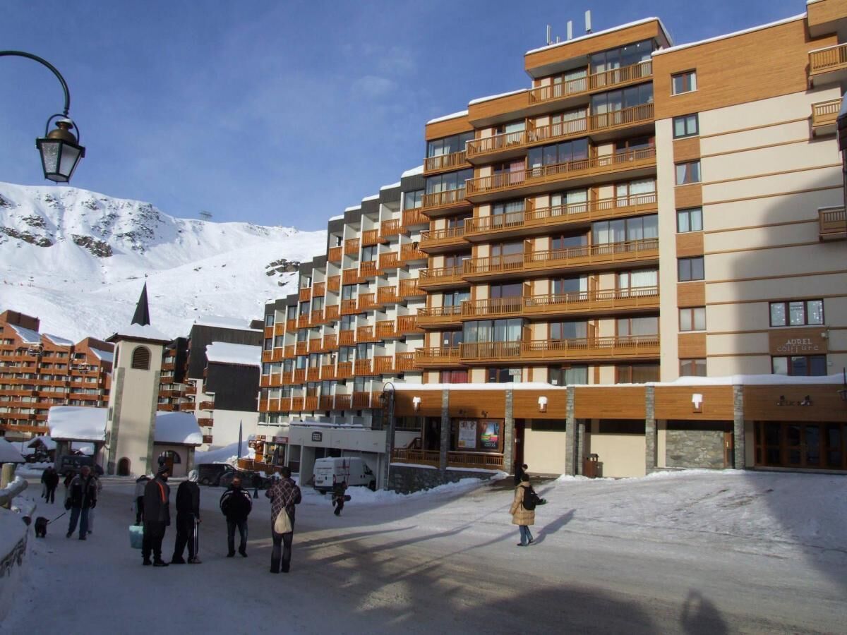 A multi-story hotel with balconies, a central courtyard, and a snowy mountain backdrop.