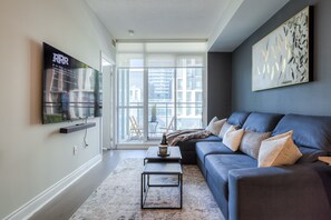 Relax in this stylish living room with a large flat-screen TV, plush sofa, and city views.