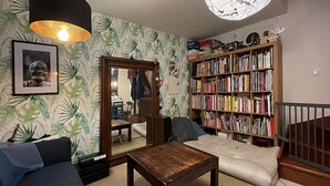 A cozy living room with a bookshelf, a sofa, a coffee table, and a mirror reflecting the room. - Un Havre de Paix en Plein Paris (Paris)