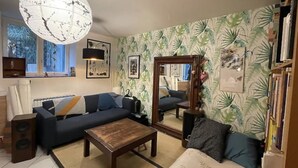 A living room with a dark blue sofa, a wooden coffee table, a large mirror, and a bookshelf. - Un Havre de Paix en Plein Paris (Paris)