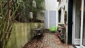 A narrow outdoor area with a wooden bench, a table, and chairs. There are potted plants and a wall with decorative elements. - Un Havre de Paix en Plein Paris (Paris)