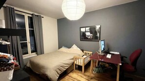 A bedroom with a bed, a desk with a computer, a chair, and a window with curtains. - Un Havre de Paix en Plein Paris (Paris)