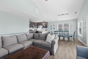 Ein modernes Wohnzimmer mit einer Eckcouch, einem Couchtisch und einem Essbereich mit Tisch und Stühlen.