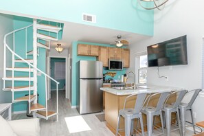 A modern kitchen with a built-in island, stainless steel appliances, and a flat-screen TV. - Aint Dat A Beach II - 2BR Upper Unit on the 2nd Row (North Topsail Beach)