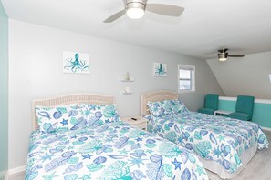 A bedroom with two beds, a ceiling fan, and artwork on the walls. - Aint Dat A Beach II - 2BR Upper Unit on the 2nd Row (North Topsail Beach)