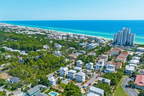 An aerial view of a coastal residential area with houses, a large hotel, and a clear view of the ocean. - 30A Home-Close to Pool-Golf Cart-Close 2 Beach (Santa Rosa Beach)