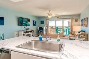 A kitchen with a sink, a dishwasher, and a view of the beach through a sliding glass door. - 715 Surf - Gorgeous 1BR Surf Condo with Washer and Dryer (Surf City)