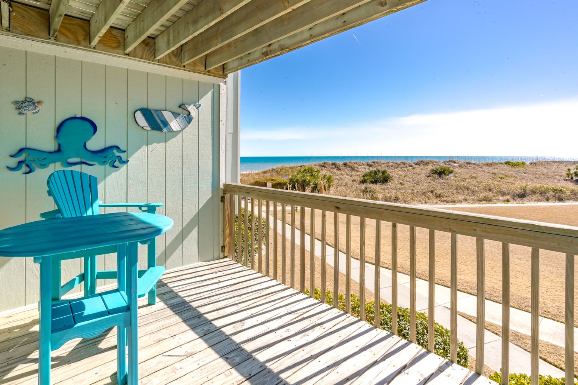 A wooden deck with a view of the beach and ocean.