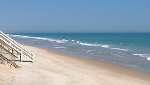 A beach with a staircase leading down to the shore, clear skies, and calm ocean waves. - 715 Surf - Gorgeous 1BR Surf Condo with Washer and Dryer (Surf City)