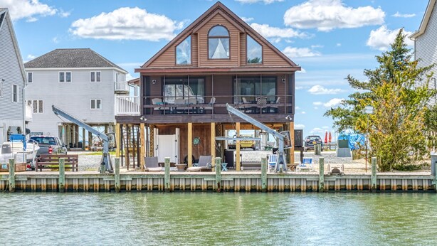 Ein zweistöckiges Haus am Wasser mit einem Steg, einem Boot und freiem Blick auf das Wasser.