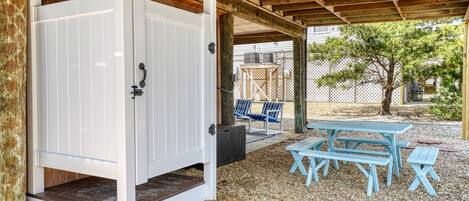 A covered outdoor area with a wooden ceiling, a white door, and a picnic table with benches.