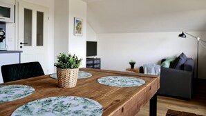 En matplats med ett träbord och stolar, en flätad korg med en växt i, och ett vardagsrum i bakgrunden.