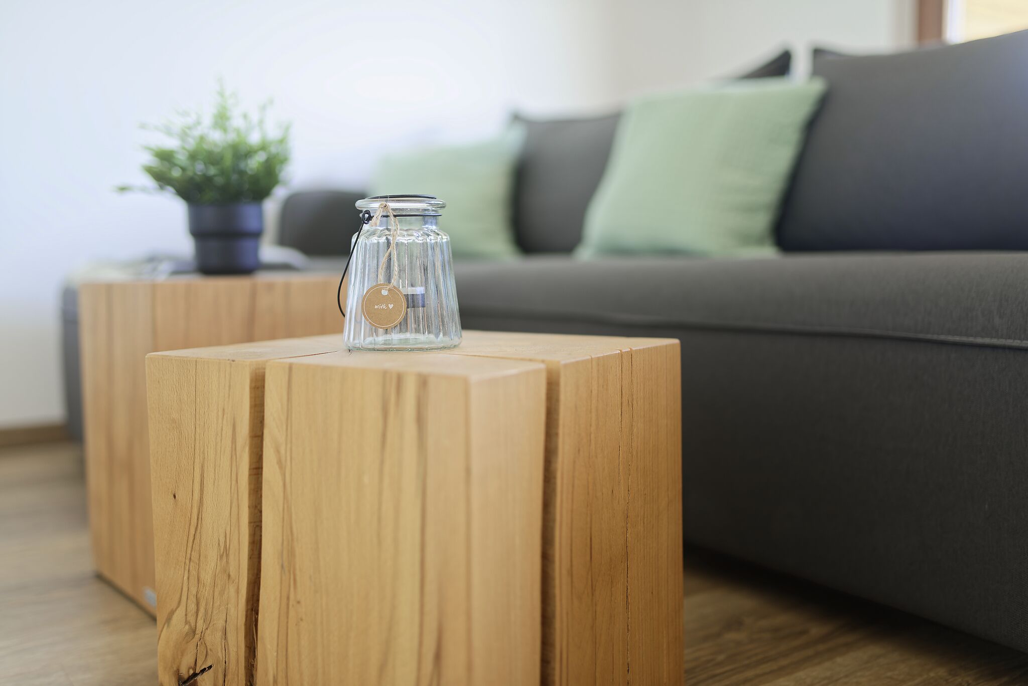 Ein Holznachttisch mit einem Glas und einer Pflanze darauf.