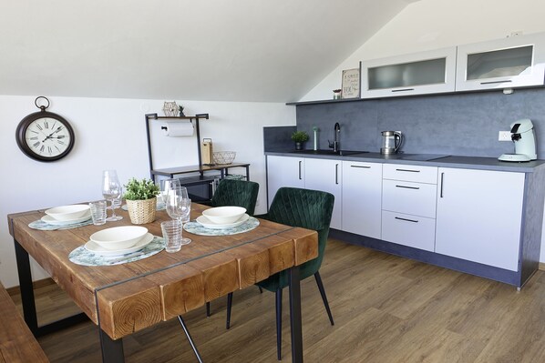 Une cuisine moderne avec des meubles blancs, une table à manger en bois et une chaise verte.