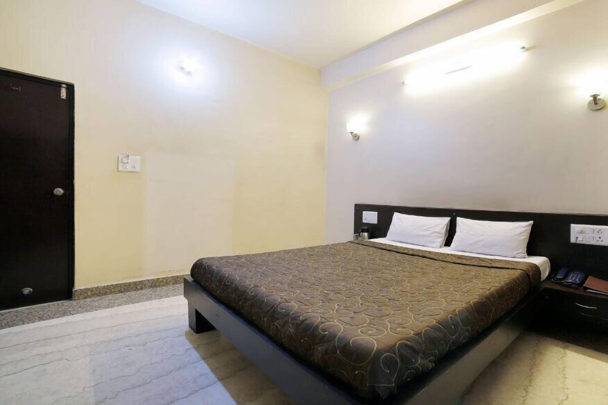 A hotel room with a bed, a nightstand, and a door.