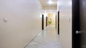 Un pasillo con suelo de mármol, paredes blancas y puertas negras.