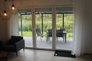 A room with a sliding glass door leading to an outdoor patio area with a table and chairs. - Ferienhaus am Seedeich (Emden)
