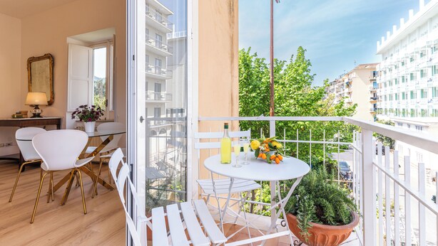 Ein Balkon mit Tisch, Stühlen, einem Blumentopf und Blick auf die Stadt.