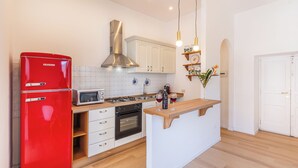 Eine moderne Küche mit einem roten Kühlschrank, weißen Schränken, einem Gasherd und einem eingebauten Backofen.