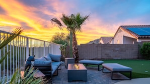 Un patio con mobiliario exterior, una chimenea y una palmera.