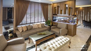 A modern living room with a sectional sofa, a coffee table, and a tufted ottoman. - Hamitbey Hotel (Istanbul)