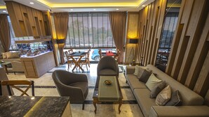 A modern hotel lobby with a marble floor, a large aquarium, comfortable seating, and a view of the street. - Hamitbey Hotel (Istanbul)