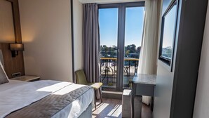 A hotel room with a large bed, a desk, and a balcony with a view. - Hamitbey Hotel (Istanbul)