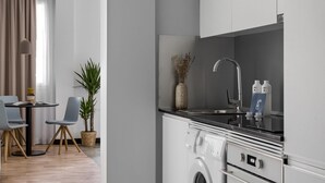 A modern kitchen with white cabinetry, a built-in washing machine, and a dining area with a table and chairs. - Bob W Madrid Atocha (Madrid)