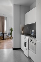 Eine moderne Küche mit weißen Schränken, einer integrierten Waschmaschine und einem Essbereich mit Tisch und Stühlen.