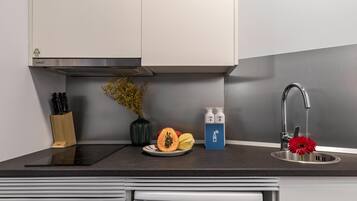 Een moderne keuken met een inbouwfornuis, een spoelbak en een aanrecht met een bloevas en een schaal fruit.