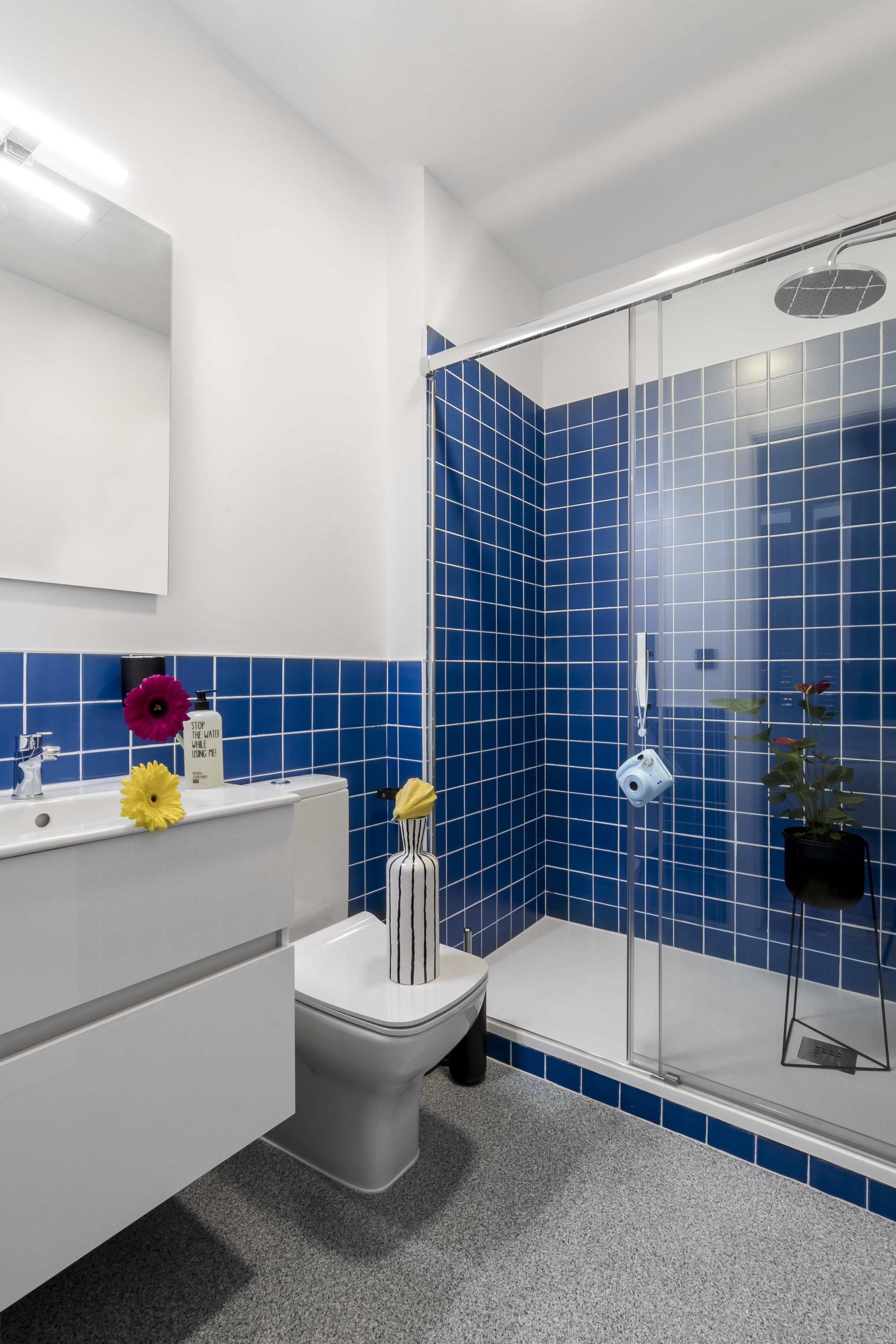 Une salle de bain avec un lavabo blanc, des toilettes et une douche à parois de verre.