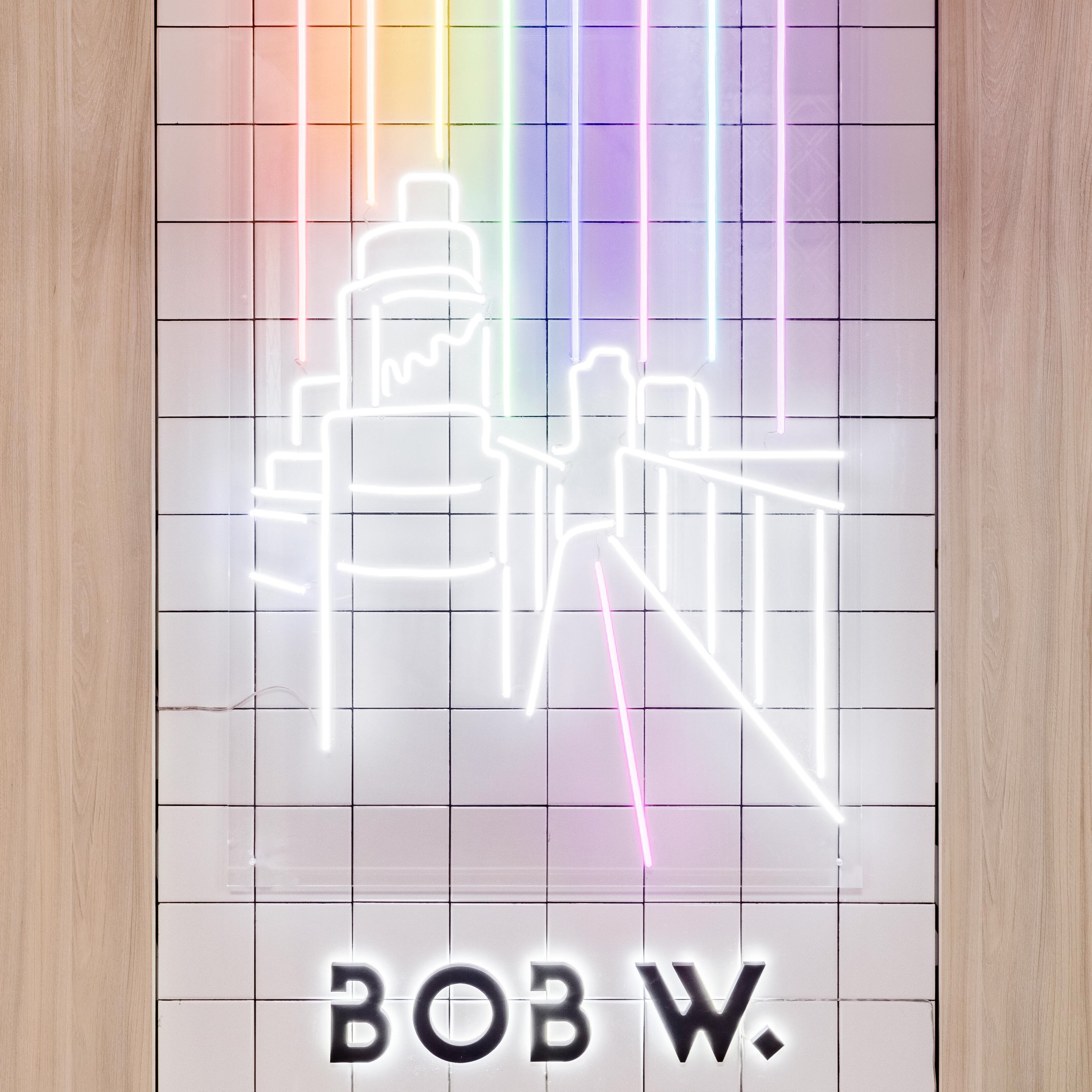 A neon sign with a cityscape design and the text "BOB W."