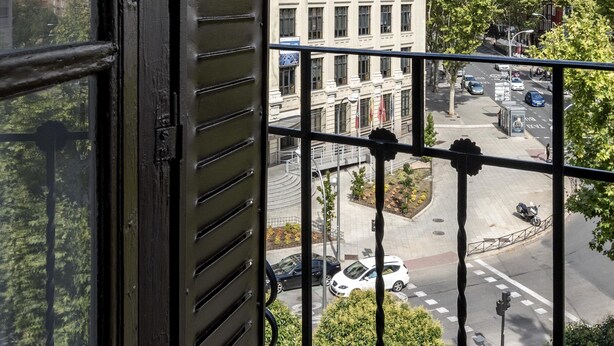 A view from a window with a metal railing, overlooking a street with buildings and trees. - Bob W Madrid Atocha (Madrid)