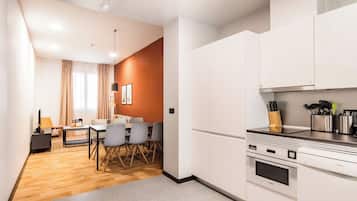 A modern kitchen with white cabinets, a Bosch oven, and a dining area with a table and chairs.