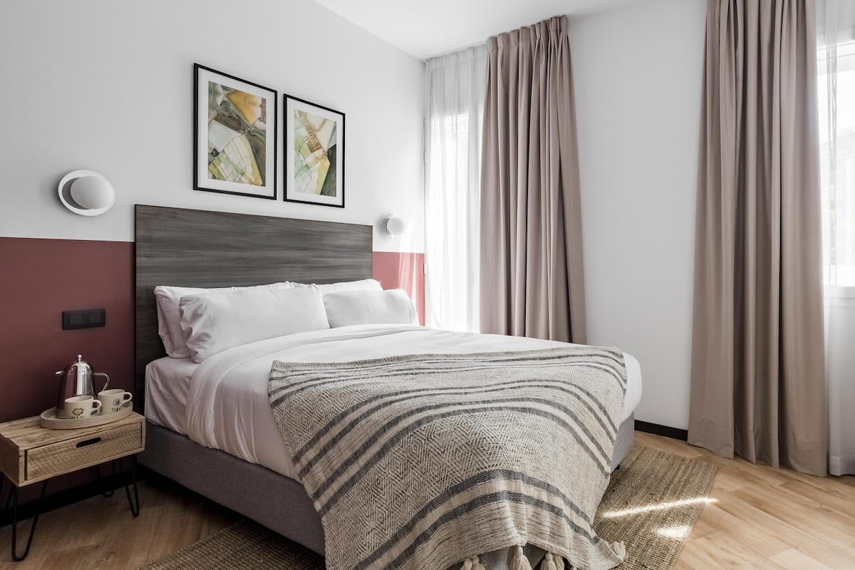 Un dormitorio moderno con cama, mesitas de noche y una obra de arte en la pared.