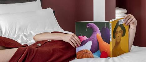 Een persoon ligt op een bed in een kamer met een witte muur, een houten hoofdbord en een rode accentmuur.