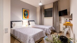 A hotel room with two beds, a television, a small table with a lamp, and a window with curtains. - Kitries Summer Getaway - Eden Sandy Suite (Kitries)