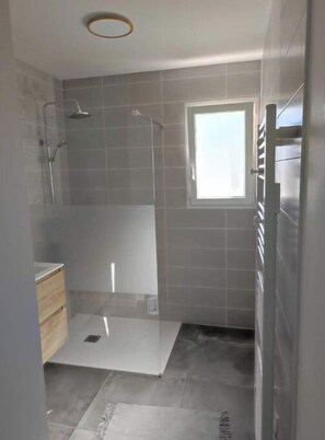 Et moderne badeværelse med bruseniche, et vindue og en indbygget vask.