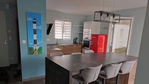 A modern kitchen with a central island, bar stools, and a red refrigerator. - Beautiful new house close to beaches and shops (Saint-Georges-d'Oléron)