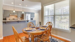 A dining area with a wooden table, four chairs, and a window with blinds. - Lakefront McCormick Gem: Deck & Golf Course Views (McCormick)
