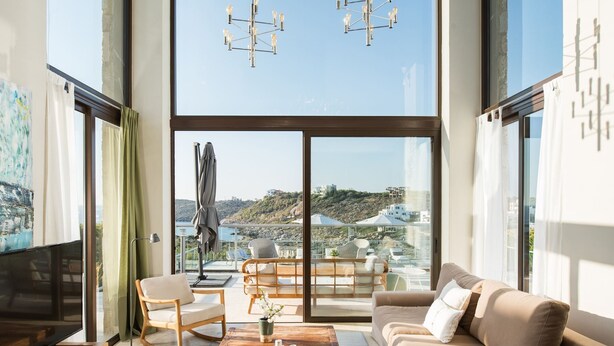 Un salon moderne doté d’un grand téléviseur, d’un canapé, d’une table basse et d’un balcon avec des sièges d’extérieur.