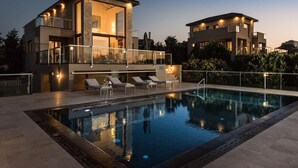 Un bâtiment moderne à deux étages doté d’une piscine, d’un espace extérieur aménagé et d’un balcon bien éclairé.