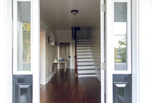 A hallway with a wooden staircase leading to an upper floor.